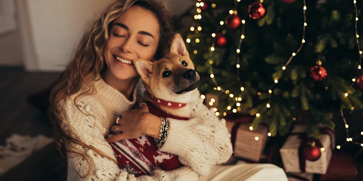 women hugging her dog christmas tree on the background